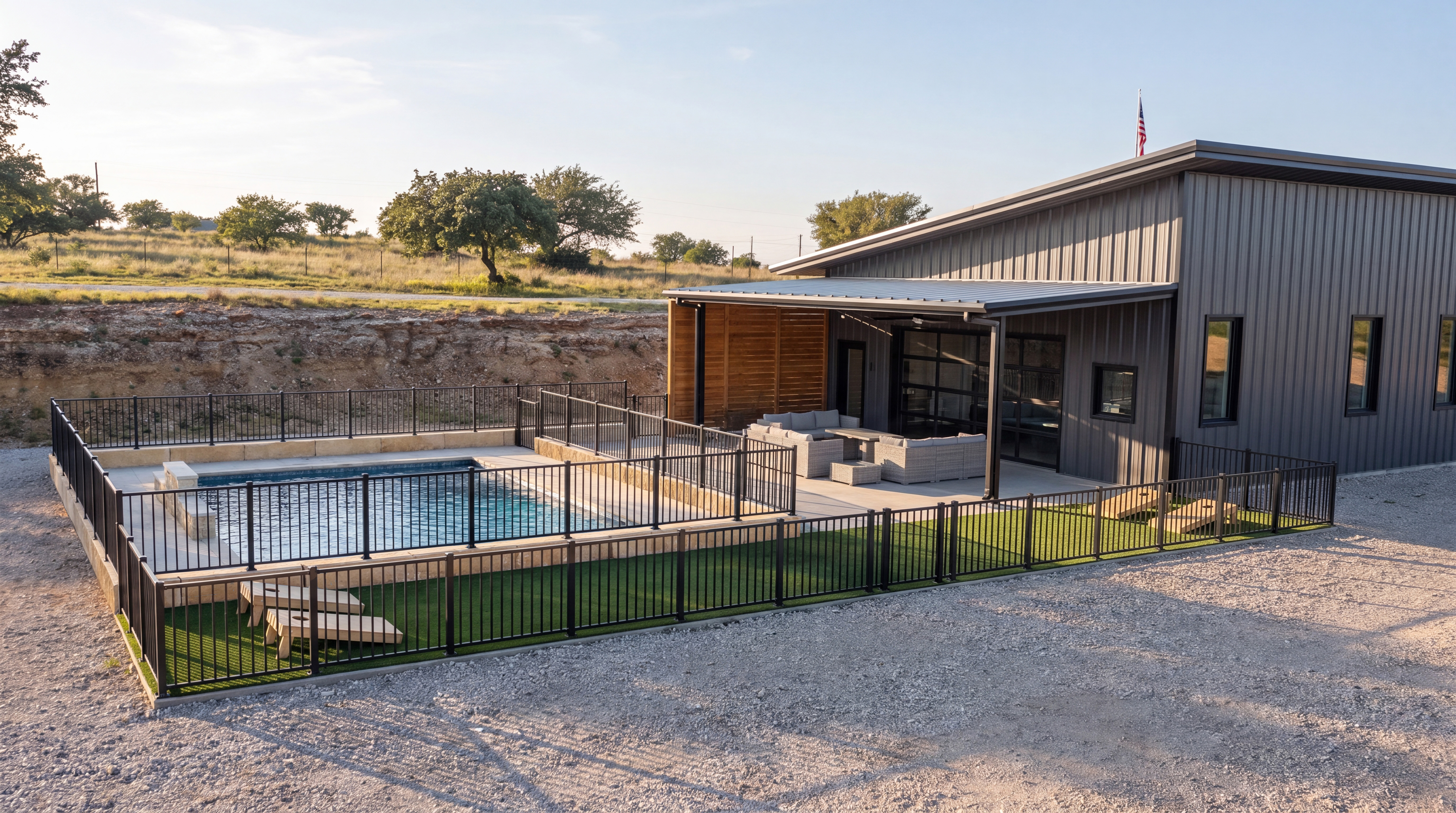 Metal barndominium with cedar screening, covered patio, pool and turf yard on a rural hilltop lot